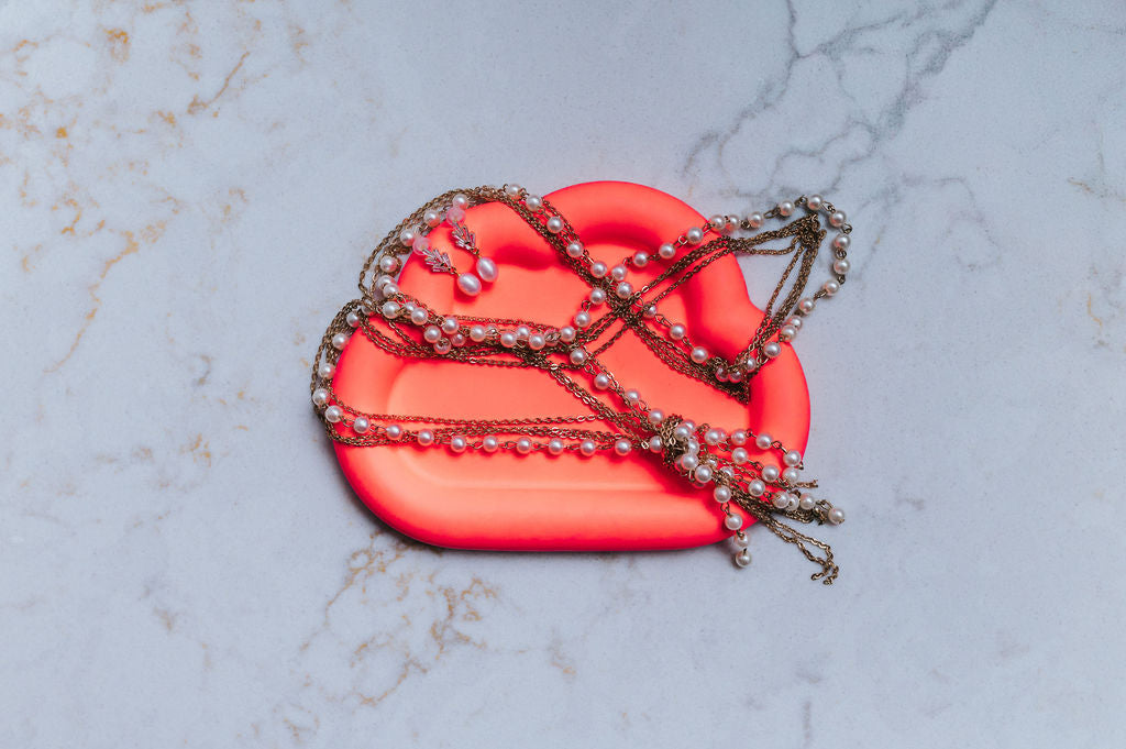 neon orange cloud shaped tray with decorative chains on a marble surface