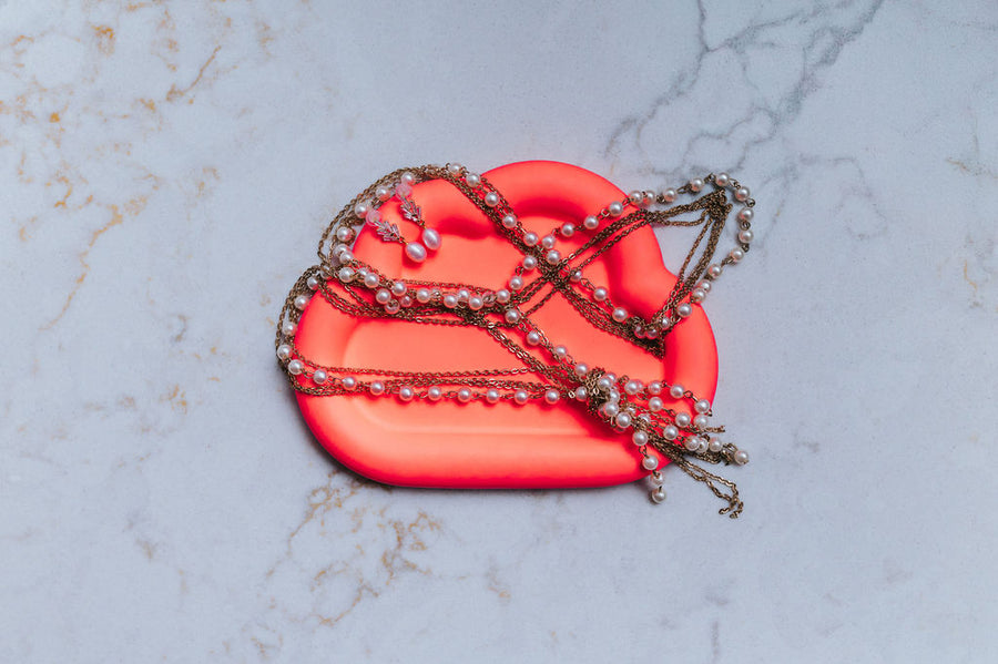 neon orange cloud shaped tray with decorative chains on a marble surface